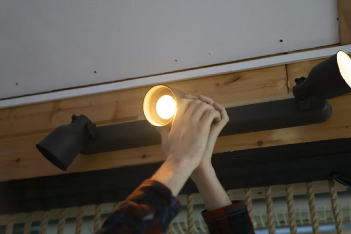 a man reaches up to replace a light bulb