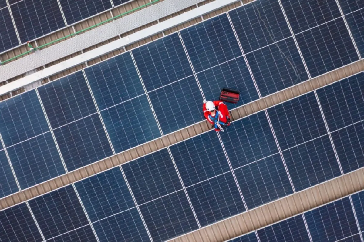 Drone view of technician installing solar panels. on the factory roof