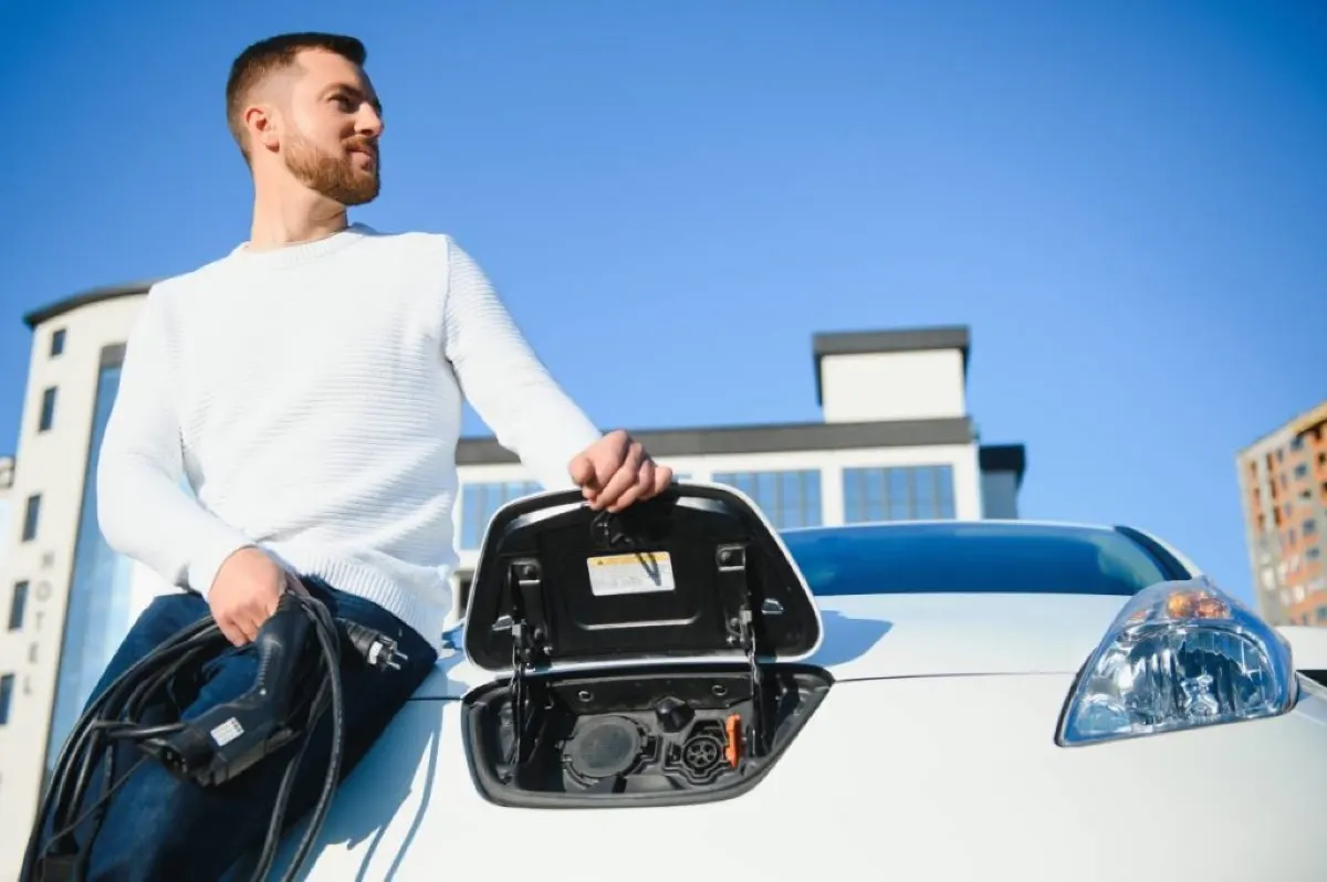 man holding an electric cable opening the charging pot of the car