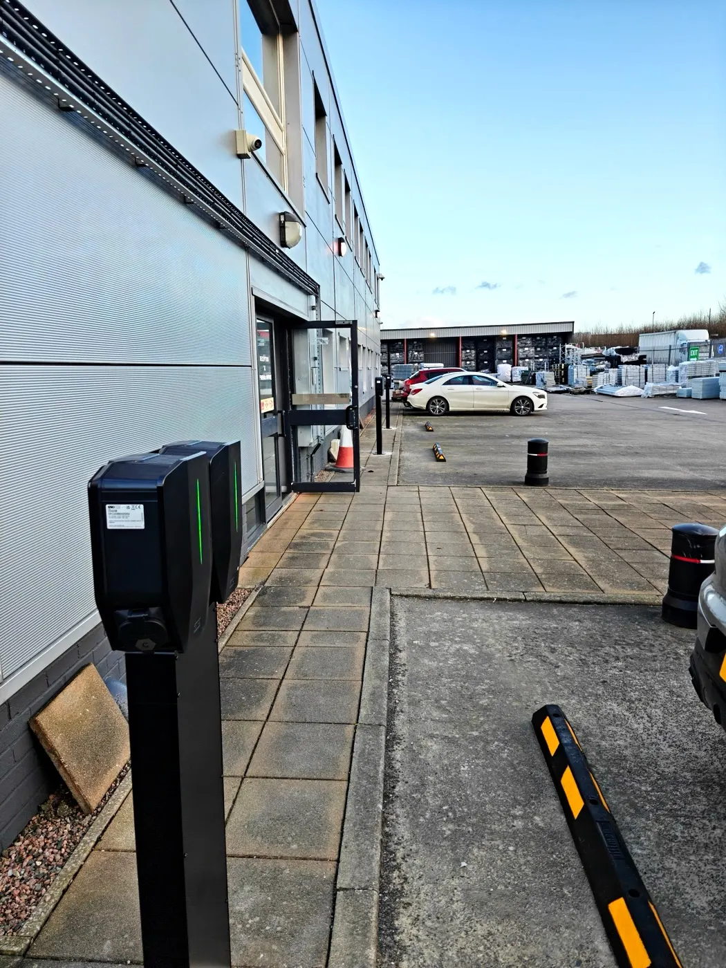 Commercial EV charge post with status light beside a business unit