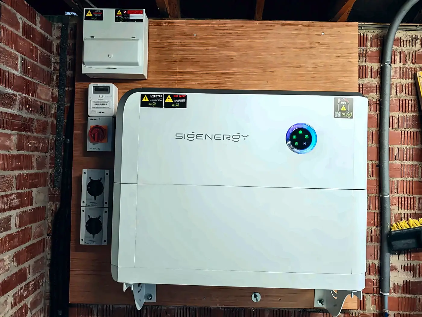 Sigenergy SigenStor wall-mounted on a garage wall beside the isolators, meter and consumer unit — Glow install, east Belfast